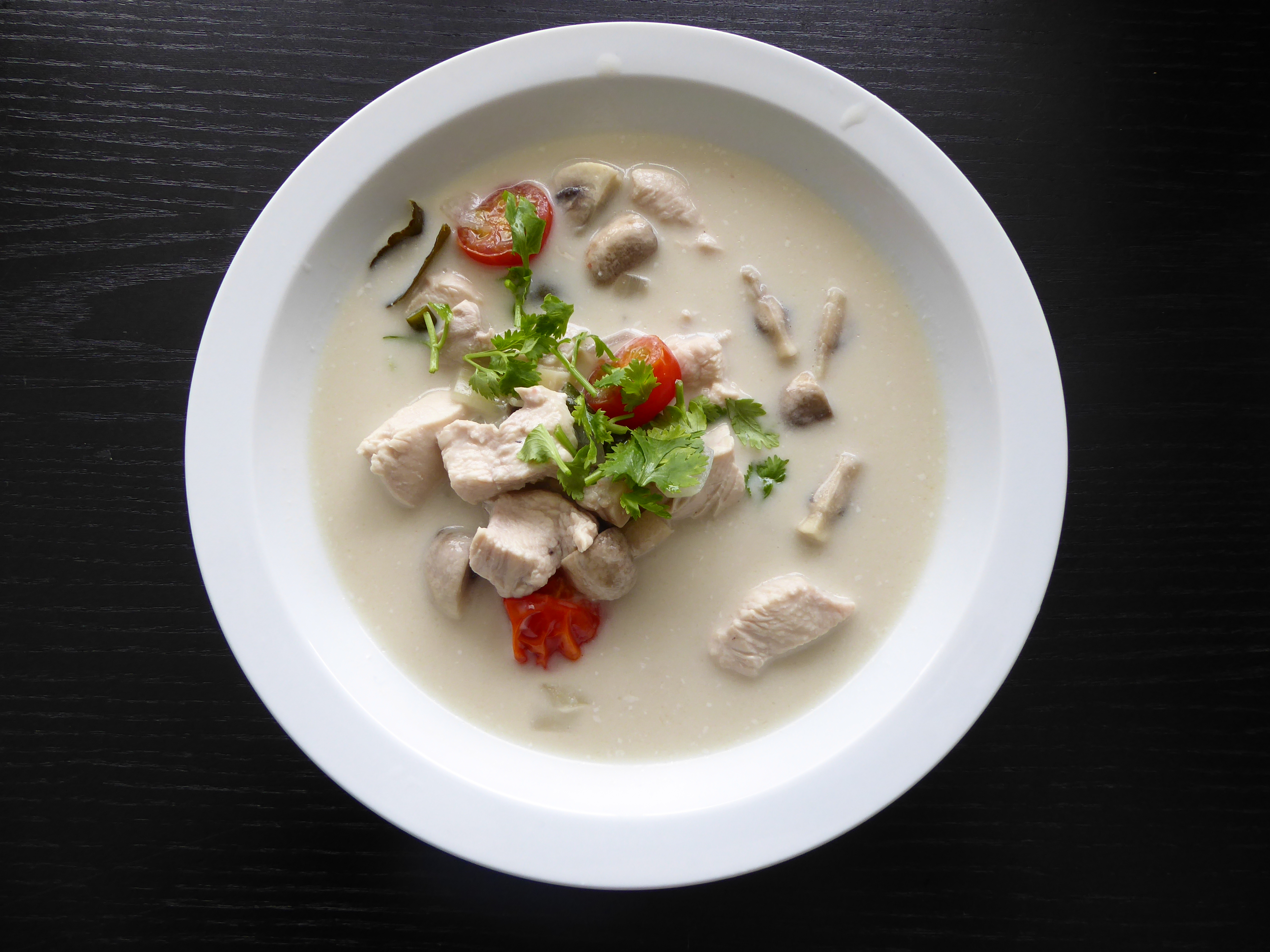 Foto van bodrje Thaise kokossoep op zwarte achtergrond